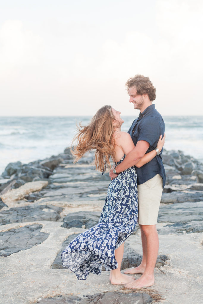 Stone Harbor Engagement Session with a blue patterned flowy dress on a rock jetty at sunset.