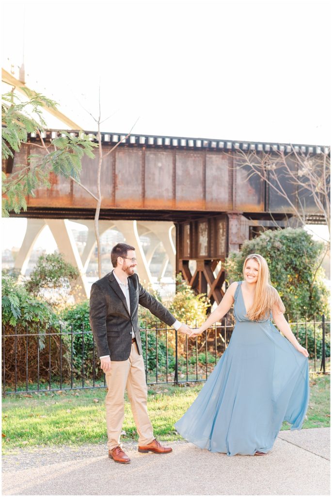 Couple smiling near bridge in dusty blue dress and suit